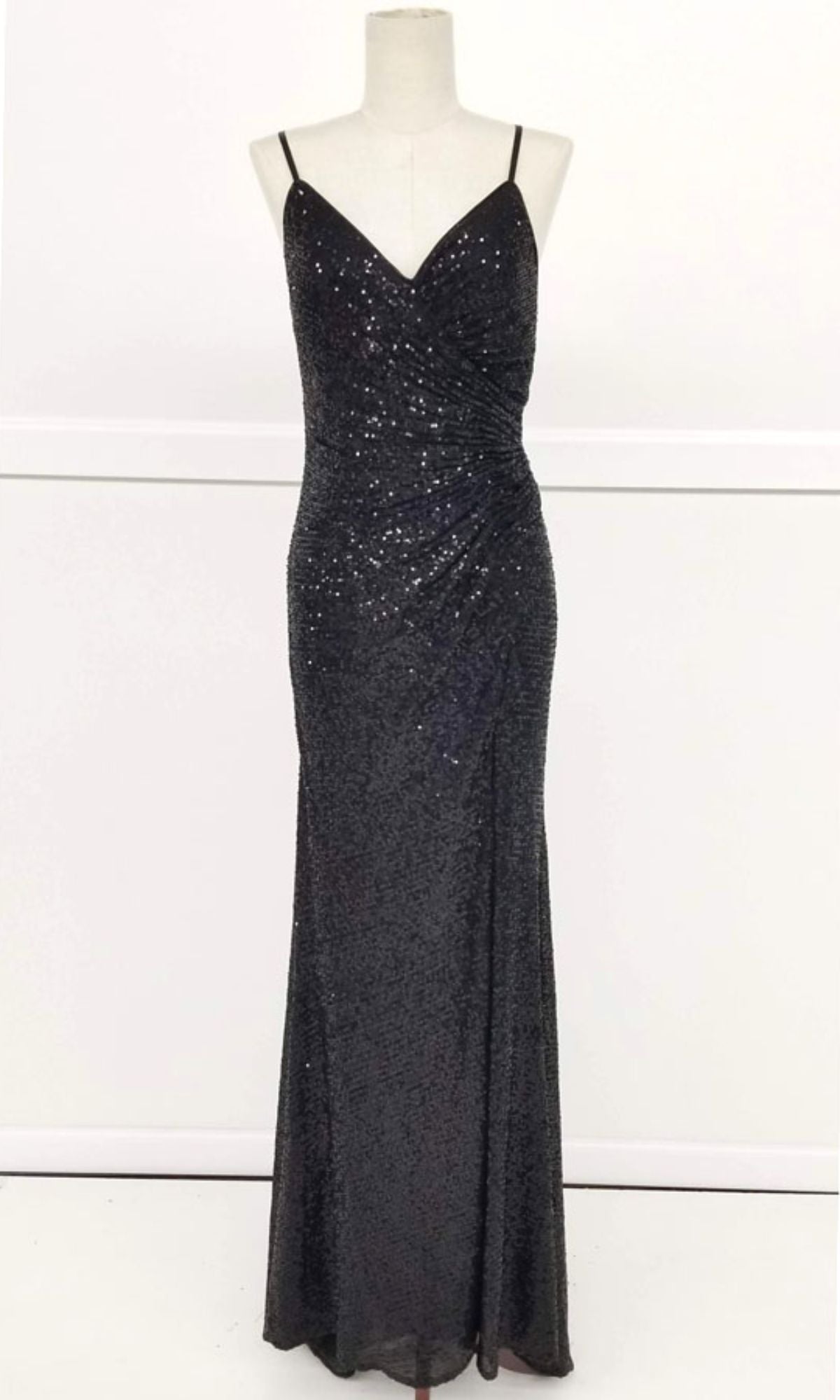 The Lace-Up Long Sequin Prom Dress: Chicas C2402 is a sleeveless, floor-length black prom dress with an open back, thin spaghetti straps, side ruching, and sparkling sequins, displayed on a dress form.